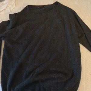 Mörkgrå kashmirtröja Oscar Jacobson -  En helt ny och oanvänd mjuk och stilren mörkgrå tröja från Oscar Jacobson i kashmir. Klassisk rund halsringning och ribbade muddar. Perfekt för dig som gillar en clean och tidlös look. Passar lika bra till jeans som till chinos.