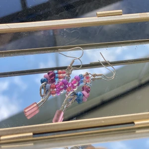 Färgglada pärlörhängen med rosa detaljer - Unika örhängen med mixade pärlor i rosa, lila, blått och rött. Hängande design med två rosa stavpärlor längst ner. Handgjord:)