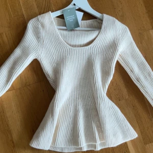 Vit ribbad topp från H&M  - Supersnygg vit ribbad topp från H&M med lång ärm och rundad halsringning. Modellen är figurnära och lätt utsvängd nertill vilket ger en fin siluett. Perfekt att styla med jeans eller kjol! Helt ny passa mig bara inte ❤️