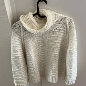 Vit stickad polotröja - Säljer en mysig vit stickad polotröja med grovstickat mönster och hög polokrage. Perfekt för kyliga dagar och enkel att matcha med jeans eller kjol. Tröjan har långa ärmar och en avslappnad passform.
