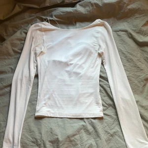 Vit långärmad topp med öppen rygg  från Gina Tricot - Säljer en vit långärmad topp med öppen rygg från Gina Tricot i storlek XS. Toppen har en tight passform och en snygg öppen rygg som ger en trendig look. Perfekt att styla med jeans eller kjol för en clean och stilren outfit.