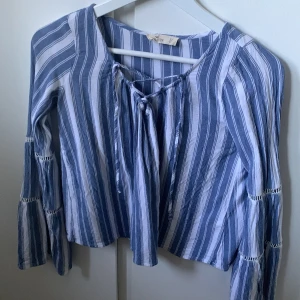 Fin somrig blus från Hollister 🌊🐚⚓️ - Super söt blus från hollister i vit / blåa ränder, perfekt för sommaren!☀️🌊 Volang ärm och snören vid halsen. Storlek: Xs - är lite kortare i modellen ❤️
