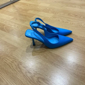 Blå klackskor med spetsig tå - Säljer ett par stilrena blå klackskor med öppen häl och spetsig tå. Skorna har en elegant design med smal klack och passar perfekt till dig som vill sticka ut med färg.