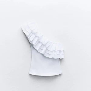 Vit oneshoulder topp med volang - Säljer min vita Zara topp. Slutsåld överallt. Perfekt till sommaren. Storlek M. Skriv för mer bilder