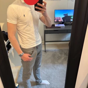 Ralph Lauren Piké - Säljer en klassisk vit t-shirt från Ralph Lauren med korta ärmar och den ikoniska broderade loggan på bröstet. T-shirten har en slim passform och är tillverkad i mjuk bomull. Perfekt för en clean och stilren look.