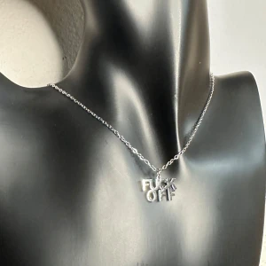 Silverfärgat halsband med textberlock - Halsband i rostfritt stål med fet metalltext: “Fuck Off”. Kedjan är ca 46 cm lång, berlocken 2 x 1 cm. Lätt, slitstarkt och med rätt attityd – ett statement som funkar både till vardags och fest. Helt nytt och redo att bäras av någon som inte kompromissar med sin stil.  Priset är redan lågt, så jag prutar inte – men bundlingrabatt erbjuds. Rensar garderob och smyckesskrin, kika gärna på mina andra annonser också!  ⸻  