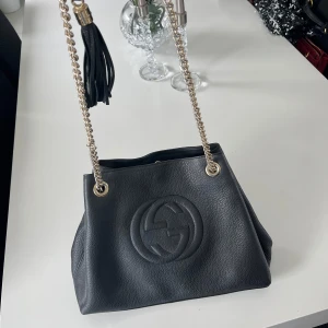 Damväska - Säljer denna snygga väska då den inte är till användning längre. Väskan är i bra skick och funkar till alla tillfällen. Den är svart med lite mönster på, och säljs till ett väldigt pris. Först till kvarn!