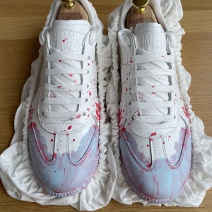 Maison Margiela Gats Splatter Paint  - Unika vita sneakers från Maison Margiela med handmålat rött och ljusblått färgstänk över hela skon. Klassisk låg modell med rund tå, snörning och exklusiv känsla i skinn. Perfekt för dig som vill sticka ut med en kreativ och edgy vibe.