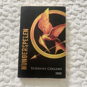 Hungerspelen - Hungerspelen är en spännande bok med en ikonisk omslagsdesign – en gyllene fågel och pil. Perfekt för dig som gillar intensiva berättelser och vill ha något som sticker ut i bokhyllan. En modern klassiker som lockar unga läsare. Lite sliten vid nedre sidan men annars ska den vara i god kvalite💞(är på svenska)