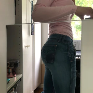 Levi's blå bootcut jeans låg midja - Säljer ett par klassiska blå jeans från Levi's med bootcut-snitt och låg midja. Jeansen har snygga slitningar, orange kontrastsömmar och detaljerad bakficka. Perfekta för dig som gillar en avslappnad men ändå trendig look. Pris kan diskuteras 