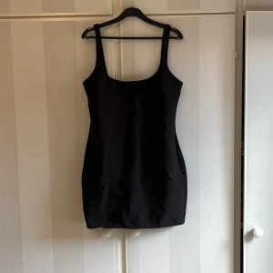 Svart tight kortklänning med breda axelband - Aldrig använd. Liten i storlek 