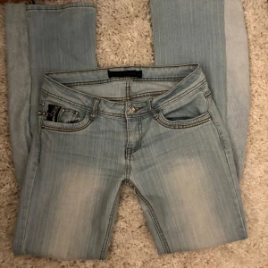 Ljusblå bootcut jeans - Säljer ett par ljusblå jeans med bootcut passform och klassiska fickor både fram och bak. Jeansen har ljusa slitningar och kontrastsömmar, samt stängs med dragkedja och knapp. Perfekta för en avslappnad stil. Finns ett hål som har sytts igen som syns på sista bilden 💕 Pris kan diskuteras💓 Passar mig som brukar ha S/M💗