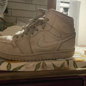 Vita Nike Air Jordans - Säljer ett par klassiska vita Nike Air Jordans med hög snörning och ikonisk logga på sidan. Perfekta för dig som älskar fina skor och vill ha en tidlös stil.