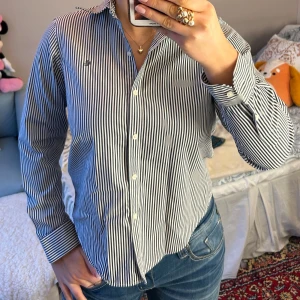 Randig skjorta från Lauren Ralph Lauren - Säljer en stilren randig skjorta från Lauren Ralph Lauren. Skjortan är i en klassisk blå och vit . Materialet är bomull och den är non-iron för enkel skötsel. 