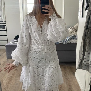 Studentklänning med broderade detaljer  - En superfin studentklänning med broderade detaljer och knappar framtill. Klänningen har långa ärmar och är v-ringad! Säljer pågrund av att jag har hittat mig en annan! Helt ny och inte använd! Nypris 999kr 