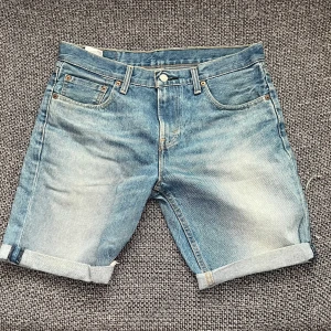 Jeansshorts från Levi's - Snygga jeansshorts från Levi's i en klassisk blå färg. De har en normal passform med fem fickor och uppvikta ben. Perfekta för en avslappnad stil. Använda fåtal gånger och är därför i nyskick! Frakt tillkommer.