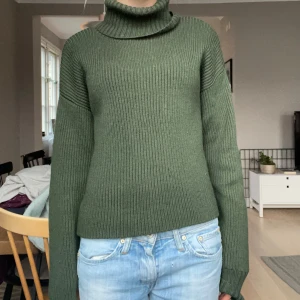 Grön stickad polotröja - Säljer en mysig grön stickad polotröja från &other storys med långa ärmar. Säljer då den inte använd längre! Tröjan har en ribbad struktur som ger extra komfort och värme. Passar bra till jeans eller kjol för en avslappnad stil.