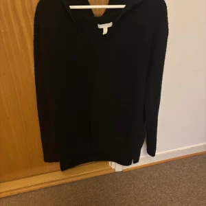 Svart stickad tröja med v-ringning - Säljer en stilren svart stickad tröja med v-ringning. Perfekt för kyligare dagar och enkel att matcha med olika outfits. Tröjan har långa ärmar och en bekväm passform.