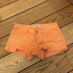 Orange shorts - Snygga orange shorts med fransiga kanter och klassisk femficksdesign. Perfekta för varma sommardagar. De har en knapp och dragkedja framtill.
