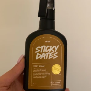 Sticky Dates Body Spray från Lush - Limited edition body spray från Lush med doft av sötma och tränoter. Flaskan är svart med en gul etikett och rymmer 200 ml. Perfekt för dig som älskar unika och varma dofter.