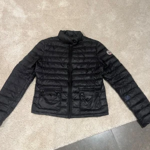 Svart dunjacka från JOTT - Säljer denna snygga dunjacka från J.O.T.T. Säljer då den inte kommer till användning, men perfekt nu till våren. Är ett litet hål med en blå ”sticker” på som knappt syns. Nästan aldrig använd, nypris 1500kr