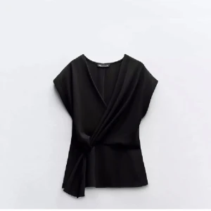 Svart omlottopp från Zara - Är storlek M men passar som S. Snygg svart omlottopp från Zara med korta ärmar och elegant drapering. Perfekt för en stilren look. Helt ny 