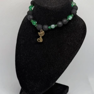 Armband med gröna och svarta pärlor - Unikt armband med gröna och svarta pärlor samt ett charmigt kattberlock i metall. Perfekt för att ge en personlig touch till din stil.