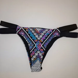 Färgglad bikiniunderdel med mönster - Snygg bikiniunderdel med ett färgglatt aztekisk mönster. Designen har dubbla svarta band på sidorna för en modern look. Passar XS -liten S