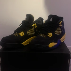Jordan 4 yellow thunders (ÄKTA) - Snygga Nike Air Jordans i svart och gult med klassisk Jumpman-logga. Skorna har snörning och en iögonfallande design med gula detaljer på sulan och ovandelen. Perfekta för dig som vill sticka ut med stil.