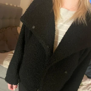 Svart teddyjacka - Mysig svart teddyjacka med stora slag och knappar framtill. Perfekt för kyligare dagar med sin fluffiga textur och avslappnade passform. En stilren och bekväm jacka som passar till många olika outfits. Från Gina💗 nypris är 599 så säljer för 499 då den är använd ett fåtal gånger🫶🫶🫶