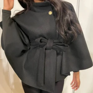 Elegant cape med knytband - Snygg cape i marinblå med hög krage och knytband i midjan. Den har en knappdetalj vid halsen och vida ärmar som ger en stilren look. Perfekt för att höja din outfit till nästa nivå. Har inga egna bilder där av låne bilder🎀