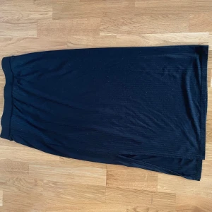 Svart långkjol - Snygg svart långkjol med en stilren design. Kjolen har en diskret slits på sidan som ger en elegant touch. Perfekt för att matcha med olika toppar och accessoarer.