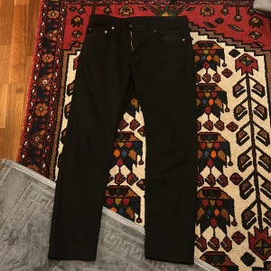 Svarta jeans från Levi's - Snygga svarta jeans från Levi's med klassisk design och fem fickor. De har en dragkedja och knapp framtill samt en liten röd Levi's etikett på bakfickan. Perfekta för en stilren look.