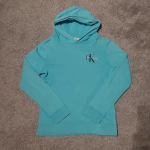 Turkos hoodie från Calvin Klein - Säljer en snygg turkos hoodie från Calvin Klein i bra skick. Barn storlek 12 alltså passar 12 år men skulle säga att den passar mindre också.