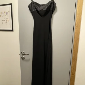 Svart långklänning - En riktig James Bond klänning, perfekt för bal eller finare tillställning. Väldigt elegant och med en snygg slit. Okänt märke. Storlek 34 men passar mig som är 36.
