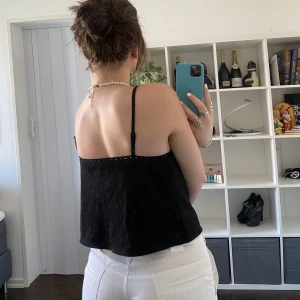 Topp - Svart topp, låg i ryggen. Detaljer som följer kanterna och framsidan av toppen 🤍🤍  Storleken står markerad som XS men passar mig som oftast har M