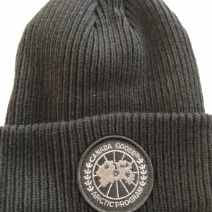 Canada Goose mössa  - Svart canada Goose mössa köpt från officiella webbplatsen, så klart har jag kvar kvitto och original förpackning.  inga returer baserat på hur den passar eller äkthets funderingar då jag har kvitto