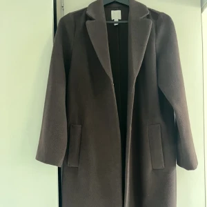 Brun kappa - Superfin mörkbrun kappa från HM i ett jättemjukt material. Använd typ 3 gånger. Färgen blir inte riktig rättvis på bild, men i en superfin mörkbrun färg.