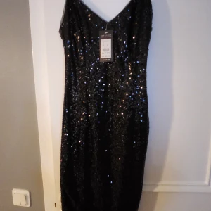 Paljettklänning - Oanvänd med prislappar kvar. Är dragkedja i ryggen, lite stretchig. Justerbara axelband. Är någon tråd som sticker ut men det ser inte ut att fattas några paljetter. 