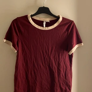 T-shirt - Vinröd t-shirt med vita muddar. Bra skick men muddarna är lite missfärgade.