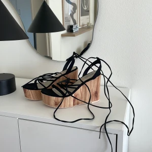 Klicklackar i trä! - Säljer dessa kilklackar i trä! Långa snören som man kan sluta hur man vill! Storlek 36. Har blivit lagade där bak se sista bilden. 