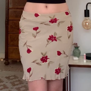 Blommig kjol - Beige meshkjol med blommigt mönster och två lager, köpt secondhand från okänt märke! Midjemåttet är 66 cm (strechig) och längden är 50 cm, står ingen storlek men är som en XS 💛
