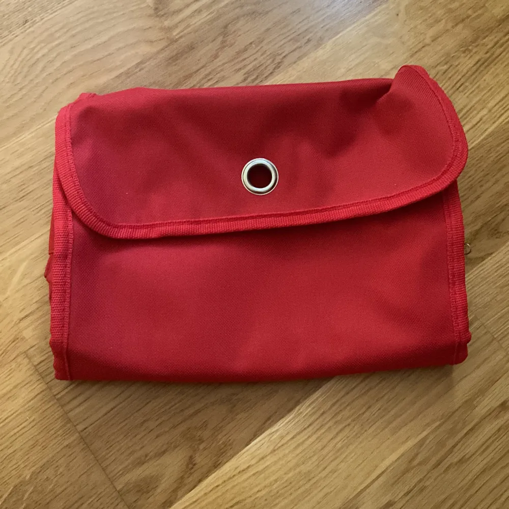 En röd necessär som går att vika upp och har flera olika fack. Den går även att hänga upp!💓. Väskor.