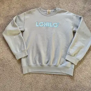 Ljusblå sweatshirt från LOHILO. Den är använd npgra gånger och tappat färgen på en viss fläck och den går tyvärr inte bort.