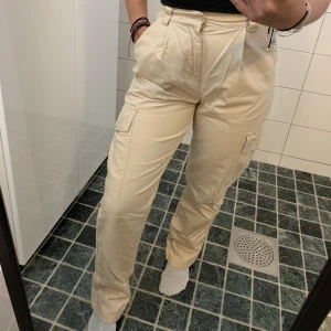 Beigea kargobyxor - Fina beigea kargobyxor, högmidjade, använda en gång och i fint skick. Jag bär strl 36 i byxor men dessa är 32:a och sitter väldigt bra på mig som ni kan se. Jag är ~ 161 cm så skulle man nog vara över 165 så kan dom va lite korta i benen.