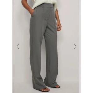 Grå Kostymbyxor NA-KD - Sjukt snygga kostymbyxor med slits vid foten. Fickor där fram. Storlek 40 men något små i storlek. Hade velat att de var lite längre, skulle säga att de blir för korta om man är 175cm+. Perfekta annars.