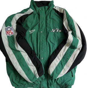 Vintage NFL reebok jacka grön - Vintage reebok nfl jets jacka från 90-talet  Jackan är i bra skick. Storlek L Personen på bild är 190