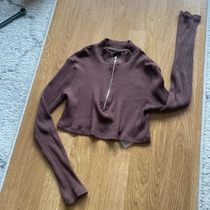 Crop top från Gina  - En brun crop top från Gina använt bara några få gånger i storlek S dragkedja du väljer själv hur högt upp du vill dra upp dragkedjan 