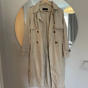 Trench från stradivarius - Säljer denna superfina trench från stradivarius då den tyvärr var lite för tight i ärmen på mig. Storlek M. Knappt använd av tidigare ägare och kan intyga att den är i bra skick! Jag är 170 och den slutar en bit nedanför knäna (sista bilden). 