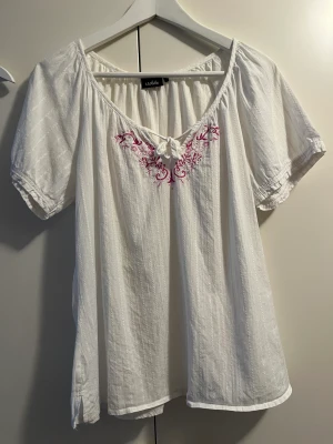 Isolde blus 44 - Fin vit blus med broderat blommönster från Isolde. Storlek 44. 